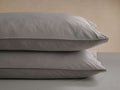Two soft gray Italian Garment-Dyed Percale Pillowcases, stacked, showing subtle texture and refined hem details.