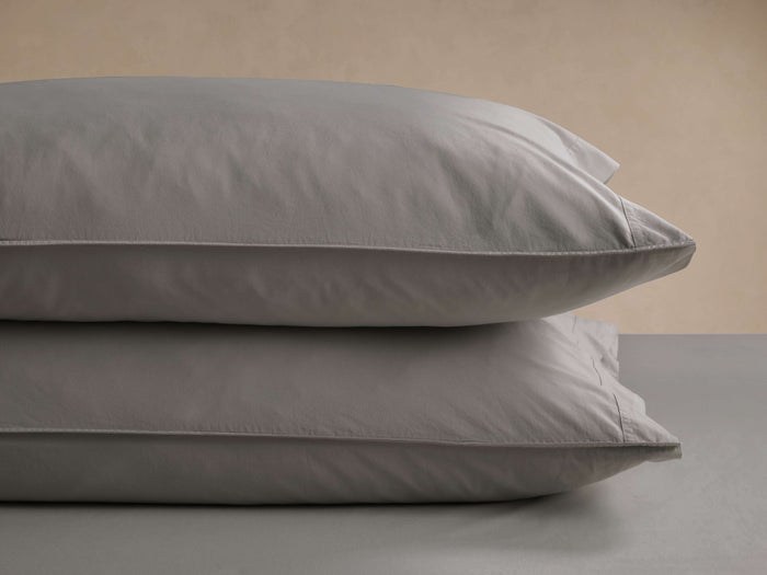 Two soft gray Italian Garment-Dyed Percale Pillowcases, stacked, showing subtle texture and refined hem details.