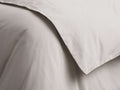 Natural Italian Garment-Dyed Sateen Duvet, close-up. Folded, smooth light gray fabric with subtle sheen and soft creases.