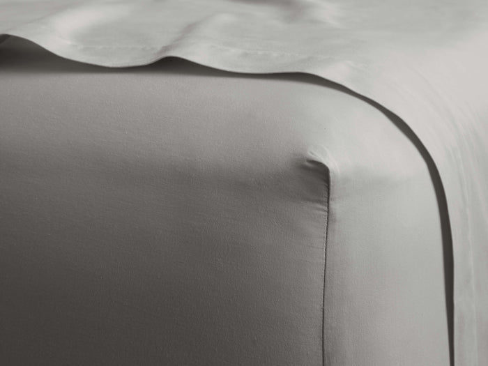 Light grey Italian Garment-Dyed Sateen Fitted Sheet corner on a mattress, showing silky fabric with subtle sheen and draped top.