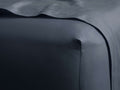 Dark blue Italian Garment-Dyed Sateen Fitted Sheet smoothly covers a bed corner, a sheet drapes over it.
