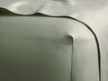 Close-up of a sage green Italian Garment-Dyed Sateen Fitted Sheet, smooth and subtly shimmering on a bed.