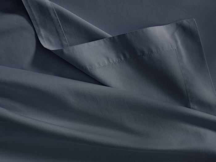 Dark blue Italian sateen flat sheet, folded, showing a wide hem with stitching and soft, flowing fabric.