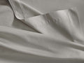 Light gray Italian Garment-Dyed Sateen Flat Sheet, folded to reveal its silky texture and a neatly stitched hem.