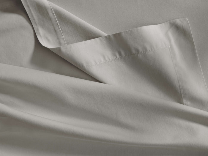Light gray Italian Garment-Dyed Sateen Flat Sheet, folded to reveal its silky texture and a neatly stitched hem.