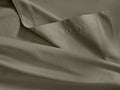 Close-up of an Italian Garment-Dyed Sateen Flat Sheet in muted sage green, showing its soft drapes, subtle sheen, and hem detail.