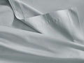 Close-up of a soft, sky-colored Italian Garment-Dyed Sateen Flat Sheet, gently folded, showing a stitched hem.