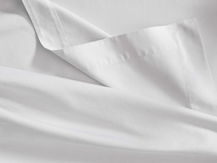 White Italian Garment-Dyed Sateen Flat Sheet, folded to reveal its smooth texture and a neat hemline stitching.