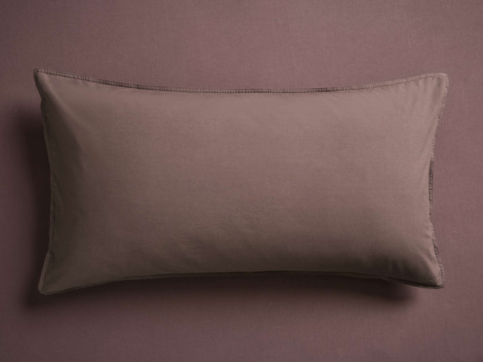 A rectangular, taupe pillow with smooth fabric and subtle stitching, placed flat against a matching taupe background.