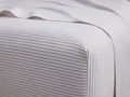 White Italian Yarn-Dyed Stripe Fitted Sheet on a bed. Thin gray stripes, horizontal on top, vertical on side.