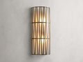 Jeunet Sconce with antiqued brass finish, features two glowing lights behind a cylindrical iron frame with vertical and diagonal lines.