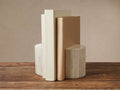Jimena Bookends: Two ivory ribbed bone inlay bookends, semicircular, holding three light-colored books on a wooden table.