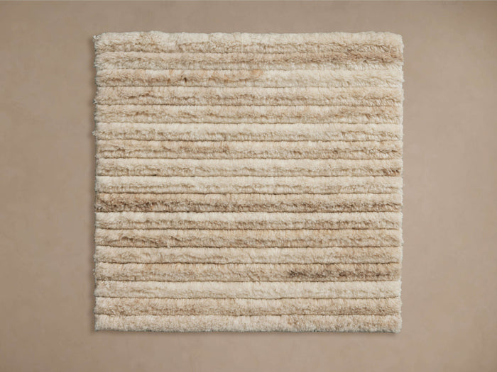 A square Kober Rug Swatch showcasing beige and cream horizontal stripes with a textured, plush surface.