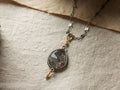 Laine Necklace featuring a black rutilated quartz teardrop pendant, 22K gold vermeil accents, and an oxidized silver chain on fabric.