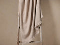 Landis Alpaca Throw, light beige with soft woven texture & fringe, draped over a rustic wooden ladder.