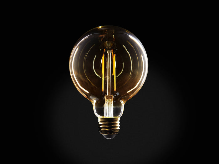 Amber glass LED G30 filament bulb with E26 base, glowing with warm light against a black background, highlighting its round shape and two-line filament.