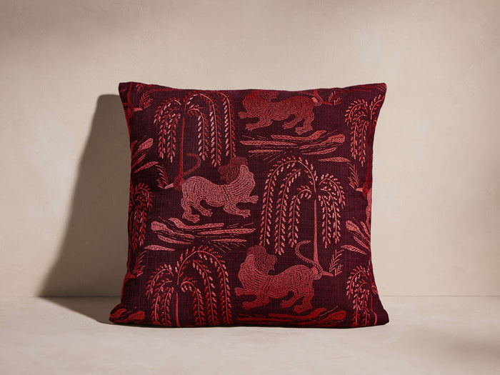 Leon Pillow; square burgundy pillow with lighter red woven pattern of stylized lions and weeping trees, facing forward.