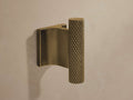 Liam Robe Hook in antique brass with knurled detailing on cylindrical hook, mounted on a flat rectangular base against a wall.