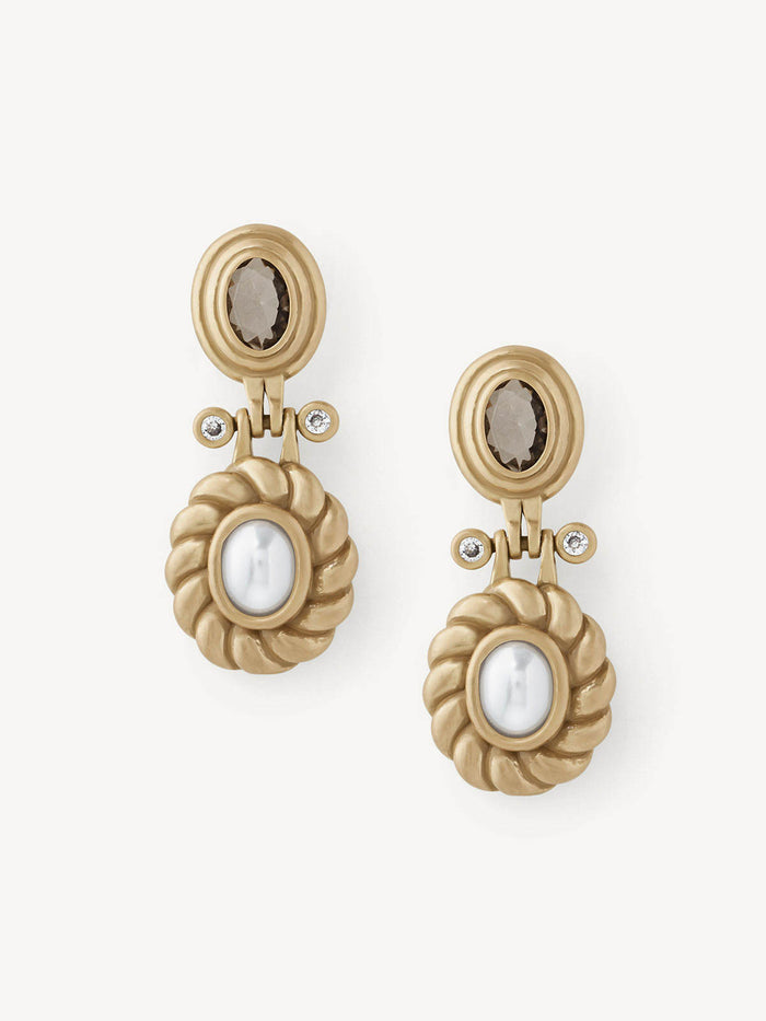 A pair of gold-toned drop earrings with oval smoky brown gemstones at the top and twisted oval white pearl-like centers below, shown on a clean off-white background.