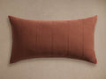 Rust-red linen lumbar pillow cover, horizontally oriented, with subtle vertical stitched lines, on a neutral background.