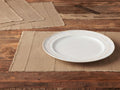 Overhead view of tan Linen Placemats (Set of 4) with frayed edges, subtle stripes, on a wooden table. One has a white plate.