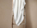White Linen Selvedge Throw draped over a rustic wooden ladder. The white fabric shows its fringed selvedge edge detail.