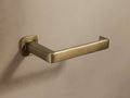 Logan Toilet Paper Holder in antique brass with an open-ended design and end stopper, mounted on a neutral wall.