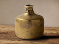 Golden antique brass Lotus Bud Vase, textured, classic round body & narrow neck, sitting on rustic wood surface.
