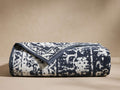 Luma Beach Towel, folded horizontally, featuring a dark blue and white timeworn printed pattern and solid blue border.