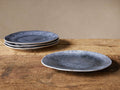 Set of 4 Luna Dinner Plates. Three stacked, deep blue reactive glazed plates with white undersides; one plate on rustic wood.