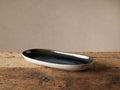 Luna Oval Platter, narrow and oval. Two-tone with glossy deep blue interior and soft white exterior, on rustic wood.