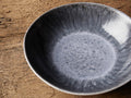 Luna Pasta Bowl showcasing a rich, deep blue interior glaze with a contrasting soft white edge, set on a rustic wooden surface.