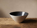 Luna Serving Bowl, handcrafted stoneware, with a deep blue reactive glaze interior and soft white exterior, resting on rustic wood.