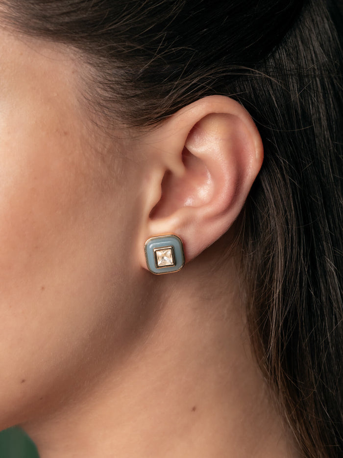 Close-up of an ear wearing a square earring with a gemstone.
