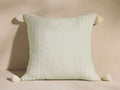 Madera Alpaca Tassel Pillow, light green with subtle woven pattern, featuring cream tassels on all four corners, on a neutral surface.