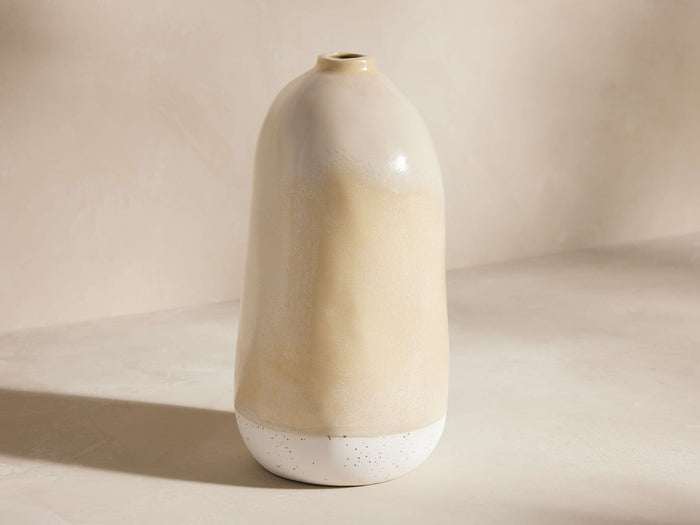 Manton Vase, a tall, organic-shaped ceramic vase with a creamy yellow glazed top and speckled white bottom, standing upright.