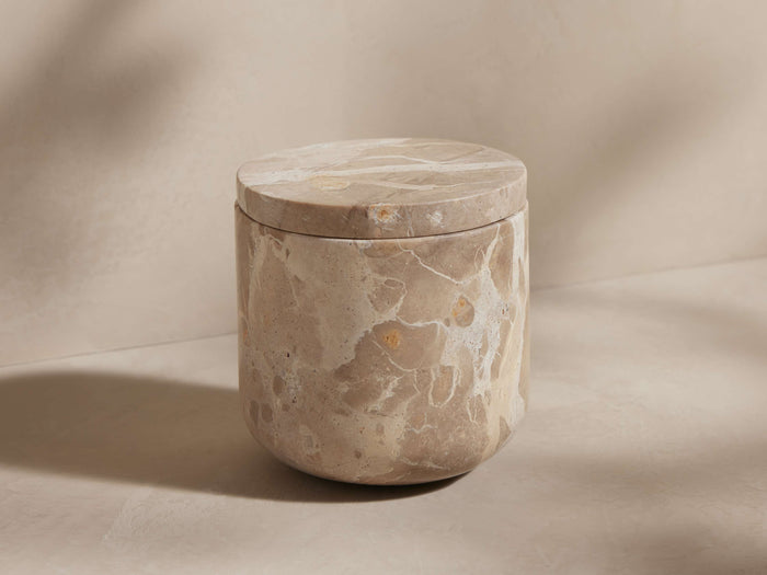 Mariyna Jar: Beige marble jar, rounded bottom, flat lid. Unique white/tan veining across the surface, bathed in soft natural light.