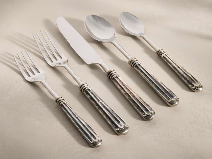 Marlene Five Piece Place Setting with shiny stainless steel tops and dark, hand-antiqued, fluted handles, arranged diagonally.