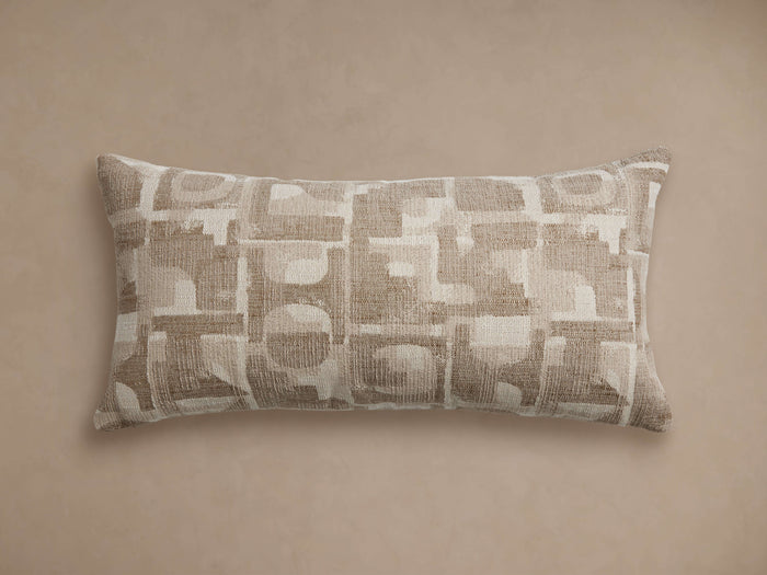 Marli Outdoor Lumbar Pillow, horizontal, with an abstract geometric pattern in monochromatic beige & tan, woven texture, on a tan background.
