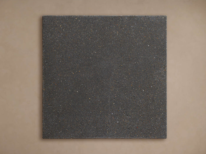 Martini Outdoor Finish Board. Square, dark grey textured finish board with small speckles, against a light brown background.