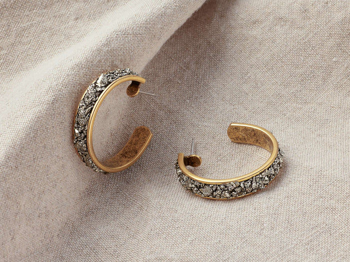 Maylin Hoop Earrings featuring gold-plated brass with textured pyrite accents, displayed on a soft fabric background.