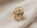Maylin Spiral Ring in gold-plated brass with a textured, twisted design, accented by glittering pyrite, resting on fabric.