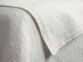 Close-up of a white Mihali Matelasse Quilt, showing its distinct textured, woven pattern with subtle raised lines and bumps.