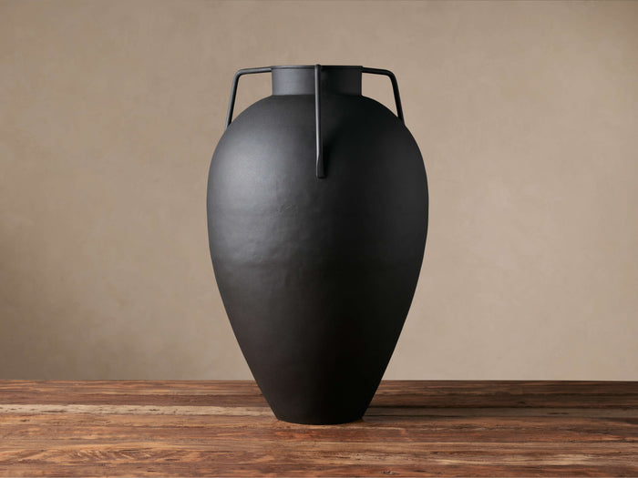 Matte black Modern Metal Vase with generous silhouette, tapered neck, and angular handles, on a wooden table.