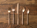 Murray Five Piece Place Setting in gold finish features a knife, two forks, and two spoons with tapered handles on wood surface.