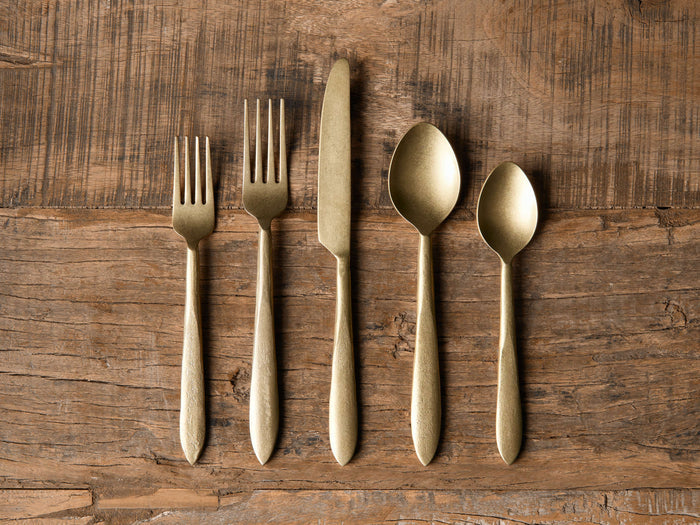 Murray Five Piece Place Setting in gold finish includes a dinner fork, salad fork, knife, tablespoon, and teaspoon on wood surface.