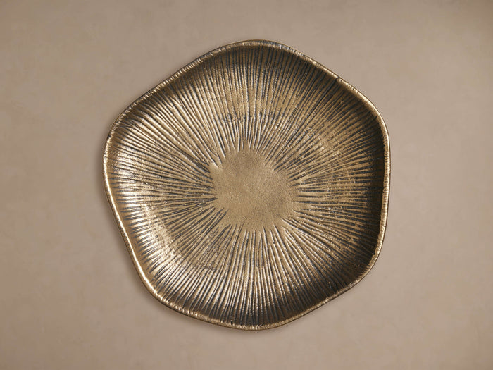 Irregular, antique brass Naomi Wall Disc with a radiating sunburst pattern, shown front-on against a light wall.