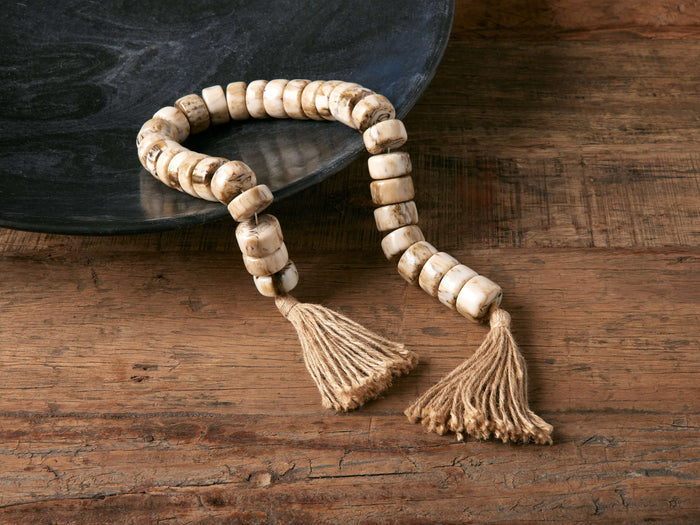 Neutral Strand featuring light-colored resin beads and jute rope, displayed on a wooden surface with a dark bowl.