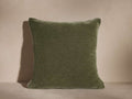 A square green velvet cushion with a soft, plush texture, shown against a neutral background, with gentle shadow on the left.