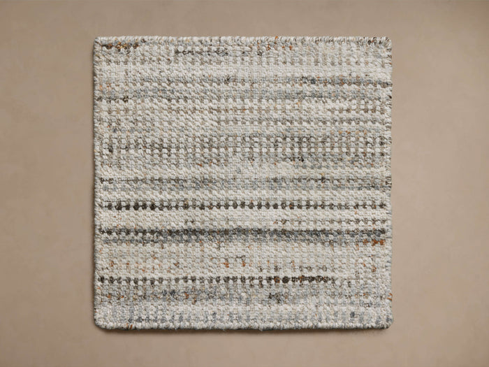 Nola Performance Rug Swatch in a square shape, displaying a textured weave with shades of gray and beige on a neutral background.